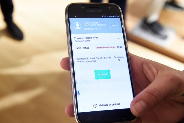O atendente recebe um aviso em seu celular de que o cliente que está no provador que experimentar outro tamanho de roupa O atendente recebe um aviso em seu celular de que o cliente que está no provador que experimentar outro tamanho de roupa