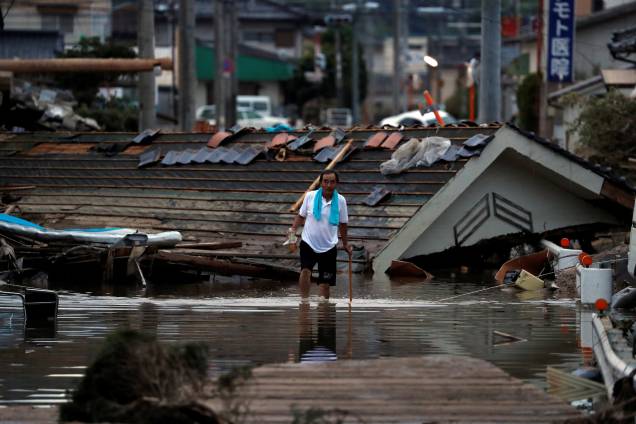 Morador caminha em frente a casas submersas e destruídas em uma área inundada na cidade de Mabi, em Kurashiki, província de Okayama, no Japão - 08/07/2018 Morador caminha em frente a casas submersas e destruídas em uma área inundada na cidade de Mabi, em Kurashiki, província de Okayama, no Japão - 08/07/2018