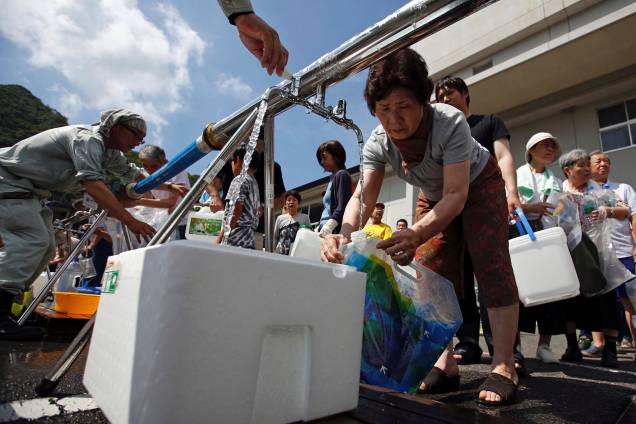 Moradores recebem água perto de uma área inundada na escola secundária Mihara Daini, que tem servido como uma estação de abastecimento de emergência, em Mihara, prefeitura de Hiroshima, no Japão - 09/07/2018 Moradores recebem água perto de uma área inundada na escola secundária Mihara Daini, que tem servido como uma estação de abastecimento de emergência, em Mihara, prefeitura de Hiroshima, no Japão - 09/07/2018