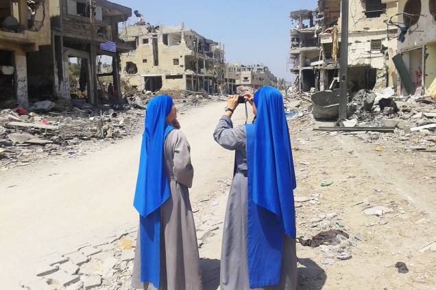 Duas freiras fotografam área destruída por bombardeios de Israel. Duas freiras fotografam área destruída por bombardeios de Israel.