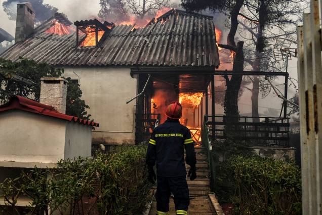 Bombeiro avista uma casa em chamas em Kineta, perto de Atenas, durante um incêndio florestal no qual 300 bombeiros, cinco aeronaves e dois helicópteros foram mobilizados para enfrentar a situação - 23/07/2018 Bombeiro avista uma casa em chamas em Kineta, perto de Atenas, durante um incêndio florestal no qual 300 bombeiros, cinco aeronaves e dois helicópteros foram mobilizados para enfrentar a situação - 23/07/2018