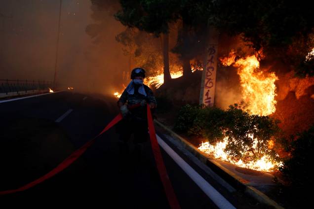 Soldado segura uma mangueira enquanto um incêndio florestal avança sobre a cidade de Rafina, perto de Atenas, na Grécia - 23/07/2018 Soldado segura uma mangueira enquanto um incêndio florestal avança sobre a cidade de Rafina, perto de Atenas, na Grécia - 23/07/2018