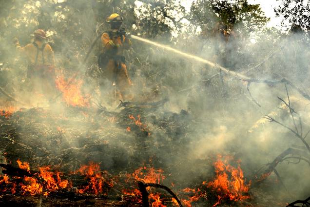 Bombeiro usa uma mangueira na tentativa de extiguir focos de incêndio em Redding, na Califórnia - 28/07/2018 Bombeiro usa uma mangueira na tentativa de extiguir focos de incêndio em Redding, na Califórnia - 28/07/2018