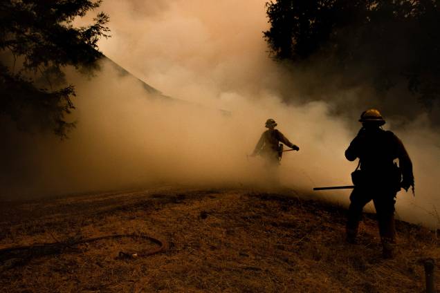 Bombeiros atravessam a fumaça enquanto as chamas se aproximam de uma casa durante o incêndio no complexo de Mendocino, em Lakeport, na Califórnia - 30/07/2018 Bombeiros atravessam a fumaça enquanto as chamas se aproximam de uma casa durante o incêndio no complexo de Mendocino, em Lakeport, na Califórnia - 30/07/2018
