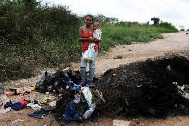 A venezuelana Joanna e seu filho Bruno, do estado de Anzoátegui, posam ao lado de seus pertences queimados por civis brasileiros, enquanto segura um pacote com fraldas doadas no controle de fronteira de Pacaraima, em Roraima - 19/08/2018 A venezuelana Joanna e seu filho Bruno, do estado de Anzoátegui, posam ao lado de seus pertences queimados por civis brasileiros, enquanto segura um pacote com fraldas doadas no controle de fronteira de Pacaraima, em Roraima - 19/08/2018