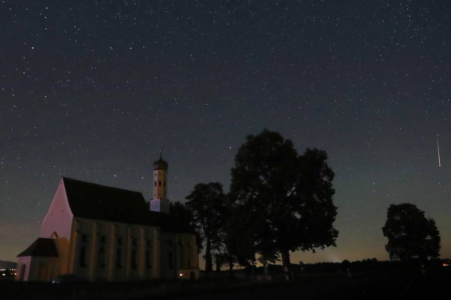 Meteoro atravessa o céu noturno atrás da igreja de peregrinação de Sankt Coloman, em Fuessen, sudoeste da Alemanha, durante a chuva anual de meteoros Perseidas - 12/08/2018