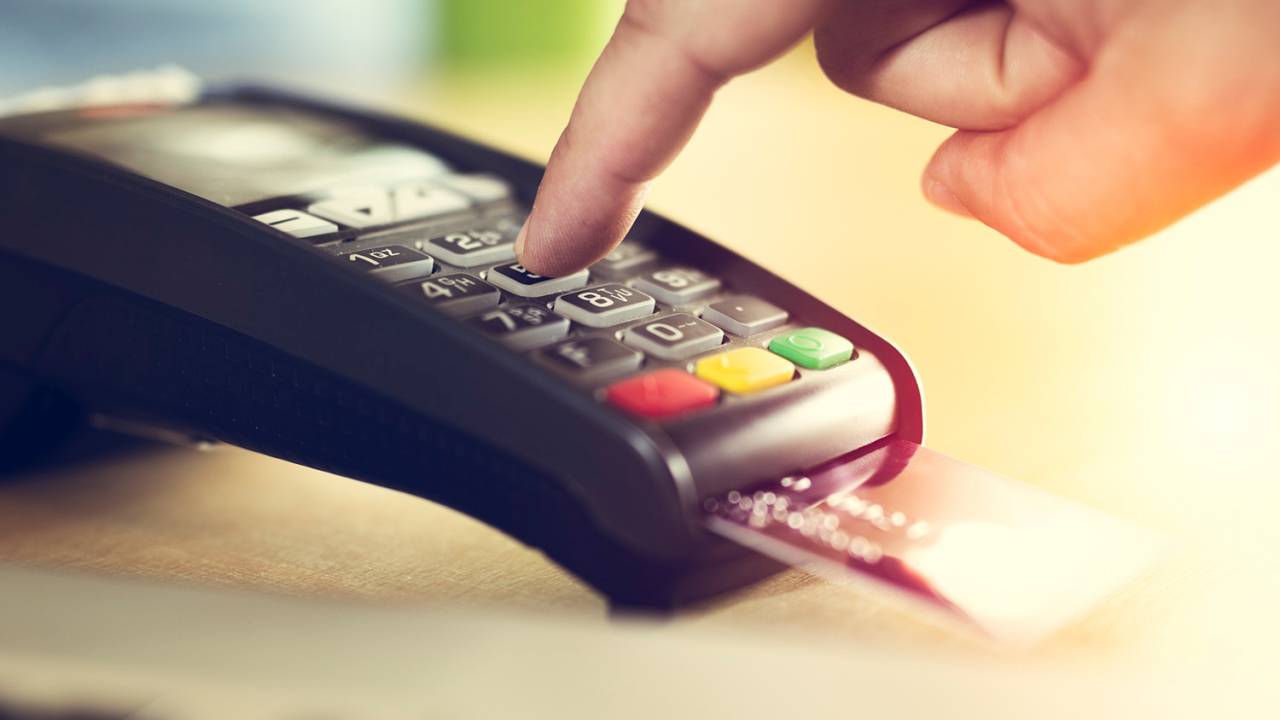 Consumidor digitando a senha do cartão de crédito ao pagar pelas compras