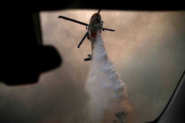 Helicóptero lança água sobre um dos focos do incêndio Woolsey em Malibu, sul Califórnia - 09/11/2018 Helicóptero lança água sobre um dos focos do incêndio Woolsey em Malibu, sul Califórnia - 09/11/2018