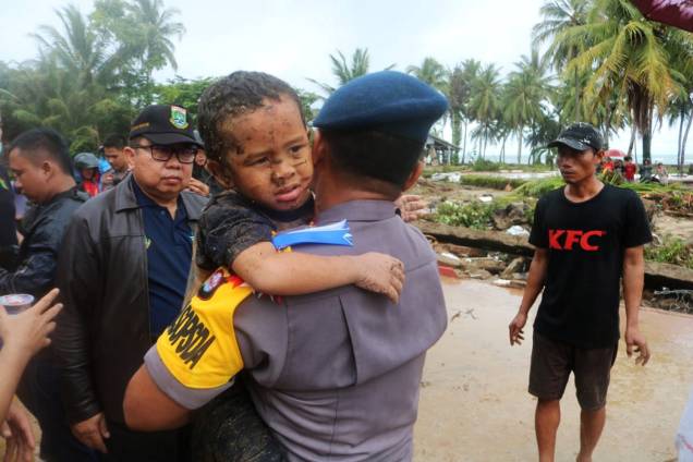 Garoto ferido é carregado por policial durante evacuação do hotel atingido por tsunami no distrito de Carita, localizado na província de Banten, na Indonésia - 23/12/2018 Garoto ferido é carregado por policial durante evacuação do hotel atingido por tsunami no distrito de Carita, localizado na província de Banten, na Indonésia - 23/12/2018