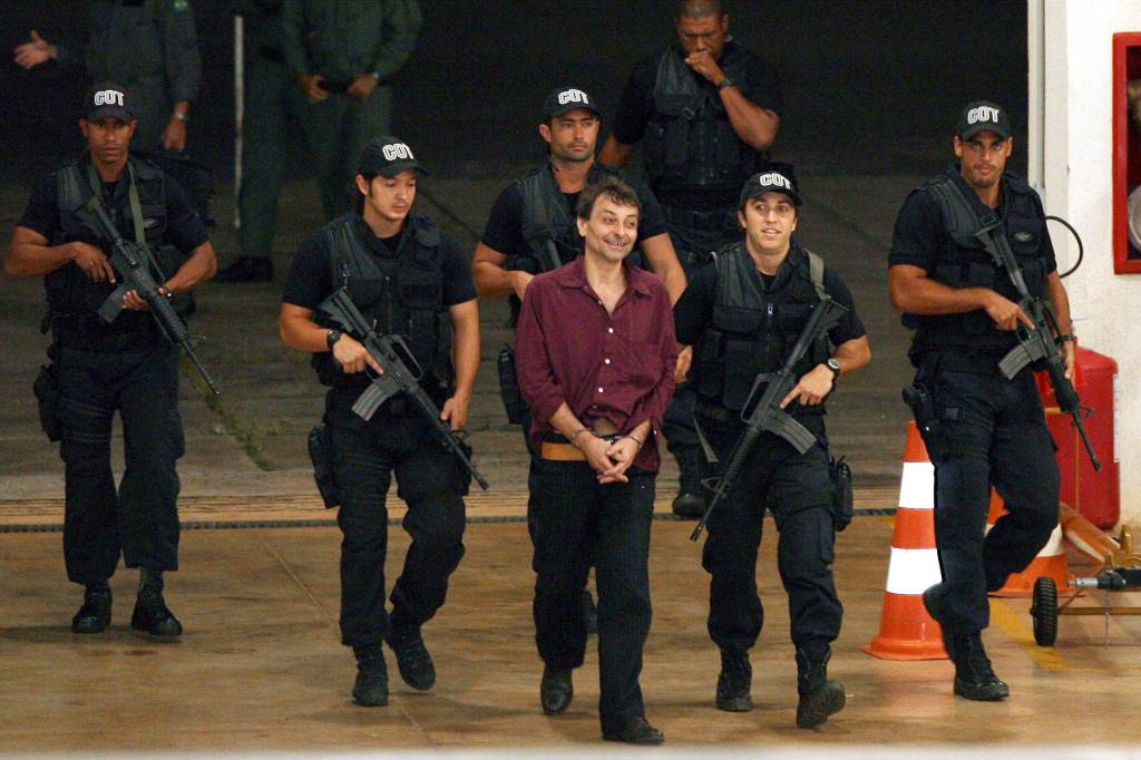 O ex-ativista de extrema esquerda italiano Cesare Battisti, 52, &eacute; escoltado por policiais da Pol&iacute;cia Federal ao chegar em Bras&iacute;lia (DF). Battisti foi um dos chefes da organiza&ccedil;&atilde;o de extrema esquerda Prolet&aacute;rios Armados pelo Comunismo. Os assassinatos pelos quais foi condenado ocorreram em 1978 e 1979. Ele foi preso no Rio de Janeiro, onde estava desde 2004 - 19/03/2007