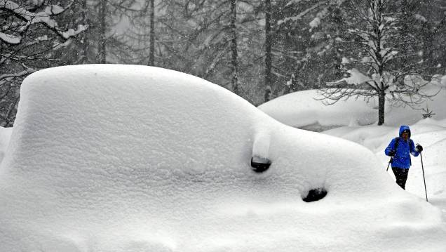 Mulher passa ao lado de um carro coberto pela neve em Ramsau am Dachstein, na Áustria - 08/01/2019 Mulher passa ao lado de um carro coberto pela neve em Ramsau am Dachstein, na Áustria - 08/01/2019