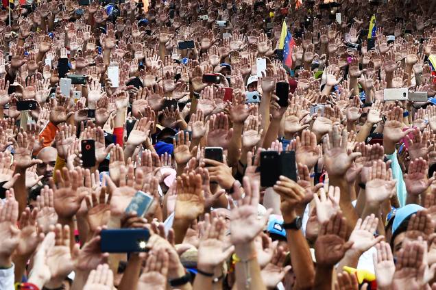 Manifestantes erguem as mãos durante juramento solene de Juan Guaidó, que se declarou presidente interino da Venezuela, durante marcha contra o governo de Nicolás Maduro, em Caracas - 23/01/2019 Manifestantes erguem as mãos durante juramento solene de Juan Guaidó, que se declarou presidente interino da Venezuela, durante marcha contra o governo de Nicolás Maduro, em Caracas - 23/01/2019