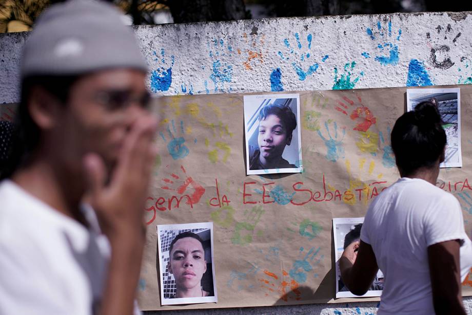 Um mural em homenagem às vítimas do massacre na Escola Raul Brasil, em Suzano, é visto atrás de alunos durante a reabertura da escola - 19/03/2019