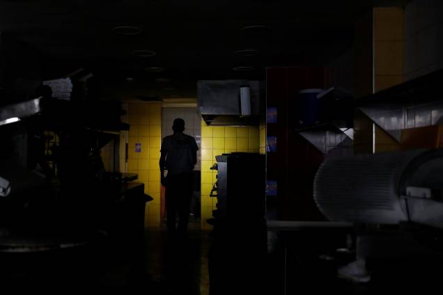 Homem usa o celular para iluminar a cozinha de um restaurante durante blecaute em Caracas, na Venezuela - 07/03/2019 Homem usa o celular para iluminar a cozinha de um restaurante durante blecaute em Caracas, na Venezuela - 07/03/2019