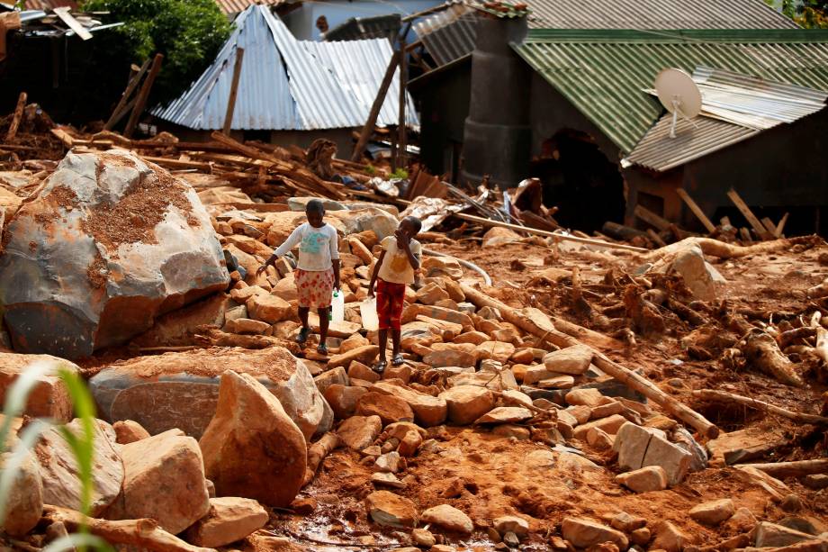 Crianças carregam galões de água entre escombros, após a passagem do ciclone Idai, na região de Chimanimani, fronteira entre o  Moçambique e o Zimbábue - 22/03/2019