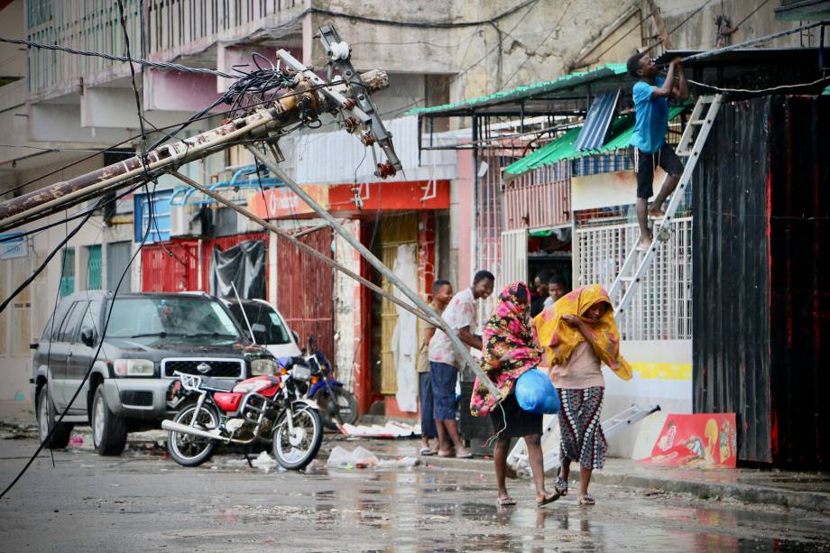 Moradores se protegem da chuva após a passagem do ciclone Idai na Beira, em Moçambique - 17/03/2019