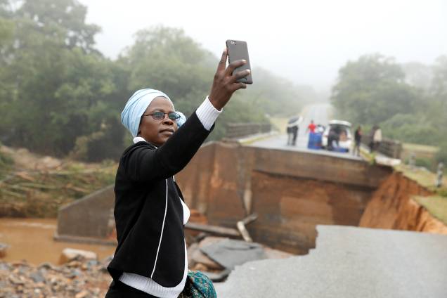 Mulher tira selfie junto de destroços de ponte que atravessa o rio Umvumvu em Chimanimani, Zimbábue - 18/03/2019 Mulher tira selfie junto de destroços de ponte que atravessa o rio Umvumvu em Chimanimani, Zimbábue - 18/03/2019