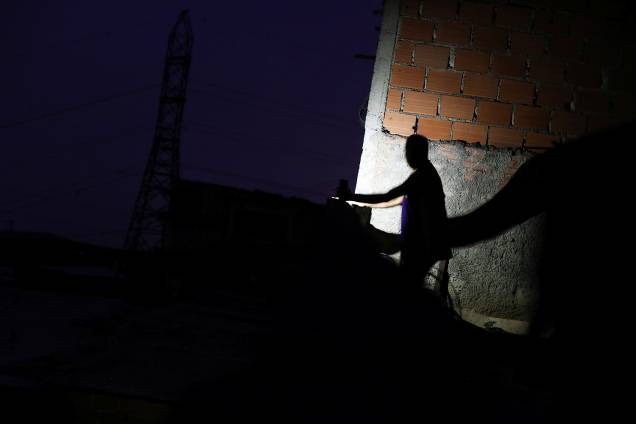 Homem utiliza lanterna de celular em bairro de Caracas, capital da Venezuela, durante apagão que atinge o país - 27/03/2019 Homem utiliza lanterna de celular em bairro de Caracas, capital da Venezuela, durante apagão que atinge o país - 27/03/2019