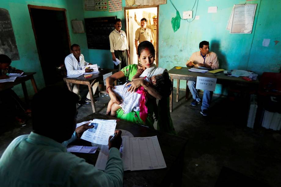 Mulher segura seu bebê enquanto aguarda para votar na primeira fase de votação em Majuli, Índia - 11/04/2019