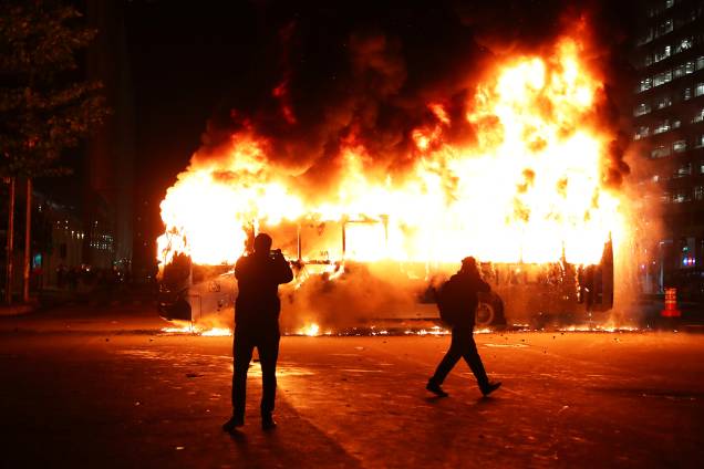 Pessoas tiram fotos de ônibus incendiado durante protesto contra o corte de verba nas universidades federais, no Rio de Janeiro (RJ) - 15/05/2019 Pessoas tiram fotos de ônibus incendiado durante protesto contra o corte de verba nas universidades federais, no Rio de Janeiro (RJ) - 15/05/2019