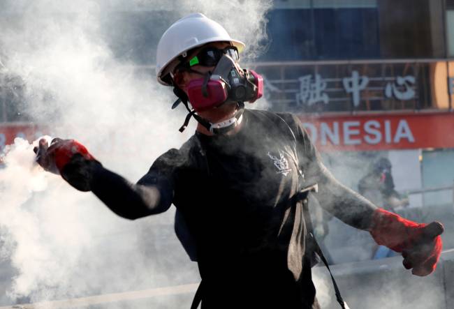 A protester throws a tear gas canister back at the police during a demonstration in support of the city-wide strike and to call for democratic reforms in Hong Kong A protester throws a tear gas canister back at the police during a demonstration in support of the city-wide strike and to call for democratic reforms in Hong Kong