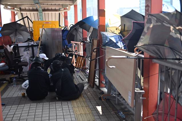 Manifestantes são vistos sentados em uma passarela barricada dentro da Universidade Politécnica no distrito de Tsim Sha Tusi durante um protesto antigovernamental em Hong Kong, China Manifestantes são vistos sentados em uma passarela barricada dentro da Universidade Politécnica no distrito de Tsim Sha Tusi durante um protesto antigovernamental em Hong Kong, China