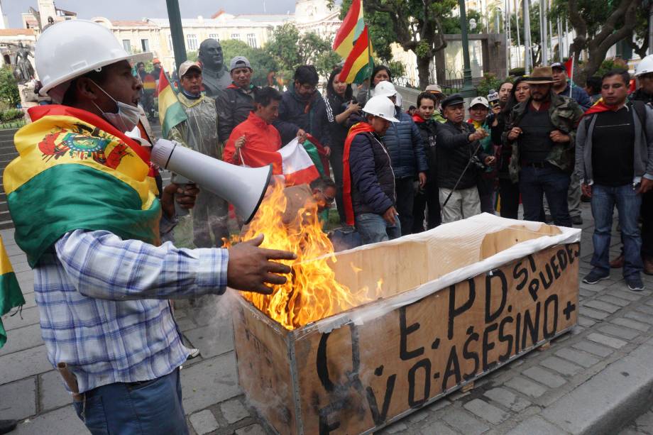 Manifestantes anti-Morales queimam uma caixa simulando um caixão com o nome de Evo Morales na antiga casa do governo Palacio Quemado, neste domingo em La Paz, Bolívia. Minutos depois, Morales anunciou sua renúncia em Chimore, Cochabamba, após três semanas de protestos por sua tentativa de reeleição depois que o exército e a polícia retiraram seu apoio.