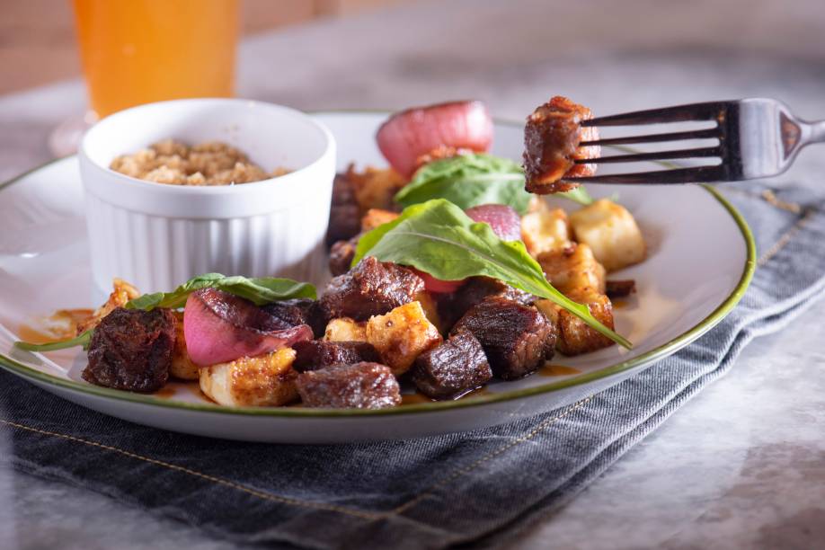 Cubinhos de carne de sol com queijo de coalho e redução de caju na companhia de farofa: forte acento regional