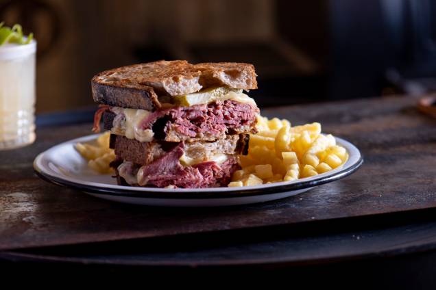 Sanduíche de pastrami feito na casa: acompanhado de mussarela, picles e mostarda, montado no pão de fermentação natural Sanduíche de pastrami feito na casa: acompanhado de mussarela, picles e mostarda, montado no pão de fermentação natural
