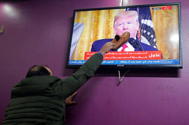 Um homem palestino coloca um sapato na boca de Trump