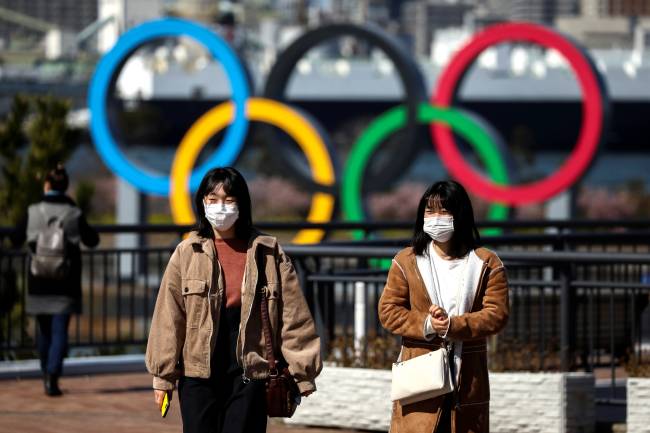 People wearing protective face masks are seen in front of the Giant Olympic rings at the waterfront area at Odaiba Marine Park in Tokyo People wearing protective face masks are seen in front of the Giant Olympic rings at the waterfront area at Odaiba Marine Park in Tokyo