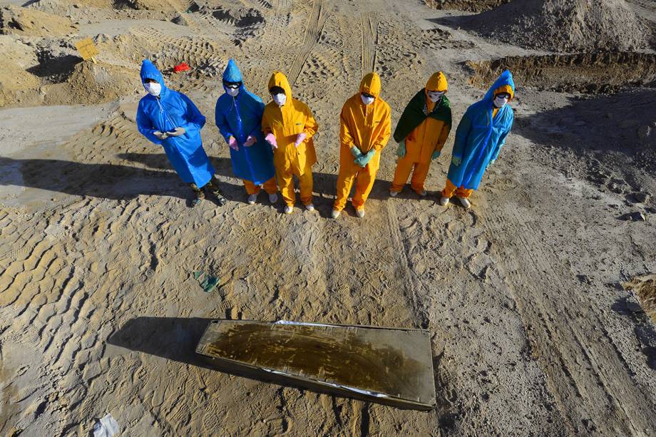 Última oração: Voluntários iraquianos rezam diante do ataúde de uma mulher de 50 anos morta pelo coronavírus antes de seu enterro em um cemitério aberto especificamente para essas vítimas