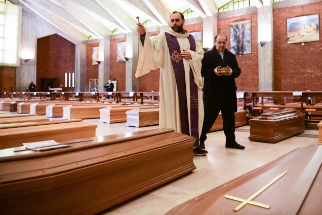 Bênção final: O padre Don Marcello asperge água benta sobre os esquifes de vítimas do coronavírus abrigados na igreja de San Giuseppe, em Seriate, na Itália Bênção final: O padre Don Marcello asperge água benta sobre os esquifes de vítimas do coronavírus abrigados na igreja de San Giuseppe, em Seriate, na Itália