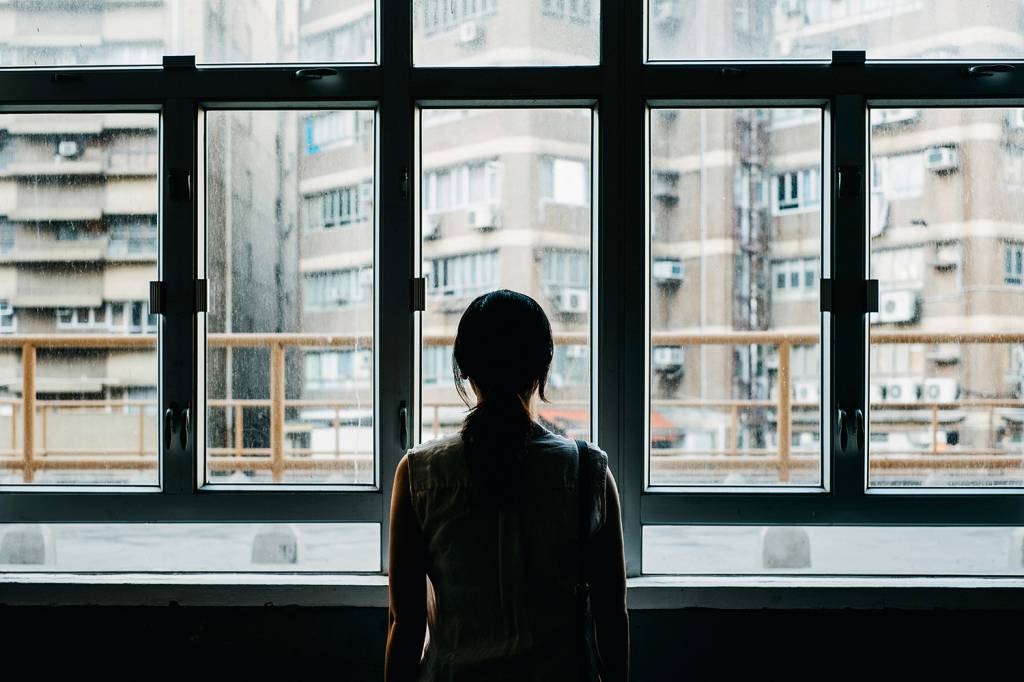 Rear view of woman looking out to city through window Rear view of woman looking out to city through window