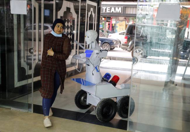 A woman enters the mall after her temperature was checked for the coronavirus, by the remote-controlled robot that has been built by the Egyptian mechanical engineer, Mahmoud El komy,limiting exposure to suspected cases, in Cairo
