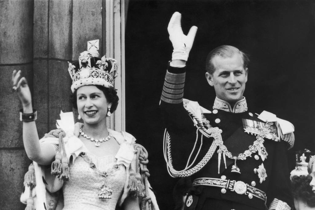 A rainha Elizabeth II e o duque de Edimburgo acenam para a multid&atilde;o na varanda do Pal&aacute;cio de Buckingham, em 1958 -