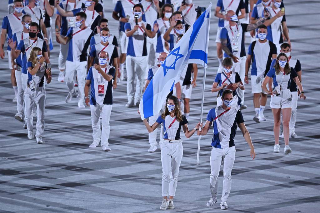Hanna Minenko e Yakov Toumarkin carregam a bandeira de Israel e lideram a delega&ccedil;&atilde;o na cerim&ocirc;nia de abertura dos Jogos Ol&iacute;mpicos de T&oacute;quio, no Est&aacute;dio Ol&iacute;mpico -