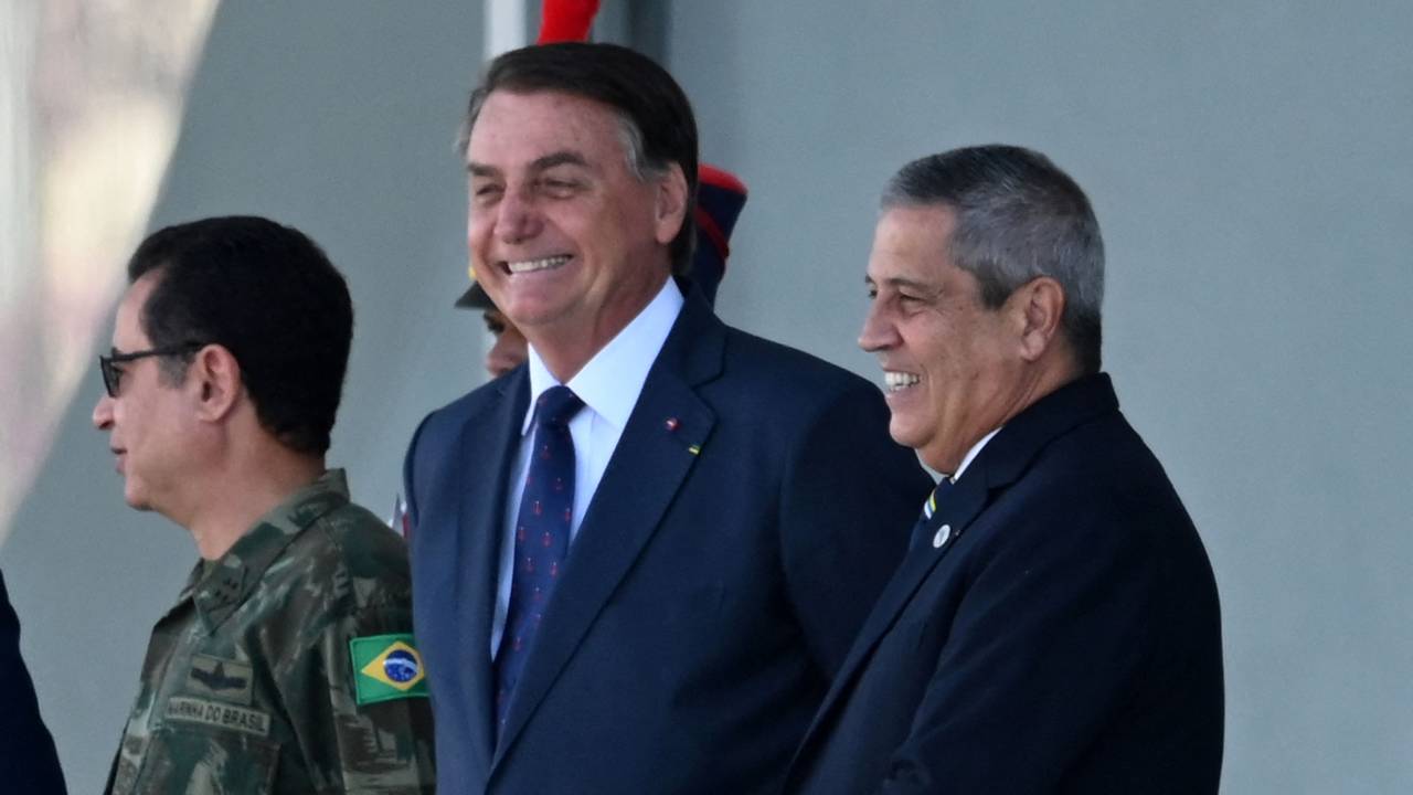 Brazilian President Jair Bolsonaro (C) smiles next to his Defense Minister Braga Netto (2R), Navy Commander Almir Garnier (L), during a military vehicles parade in front of the Planalto Palace in Brasilia, on August 10, 2021. - Bolsonaro is accused of using the armed forces for a show of force to intimidate National Congress, where a bill is being debated to modify the electronic voting system. (Photo by EVARISTO SA / AFP)