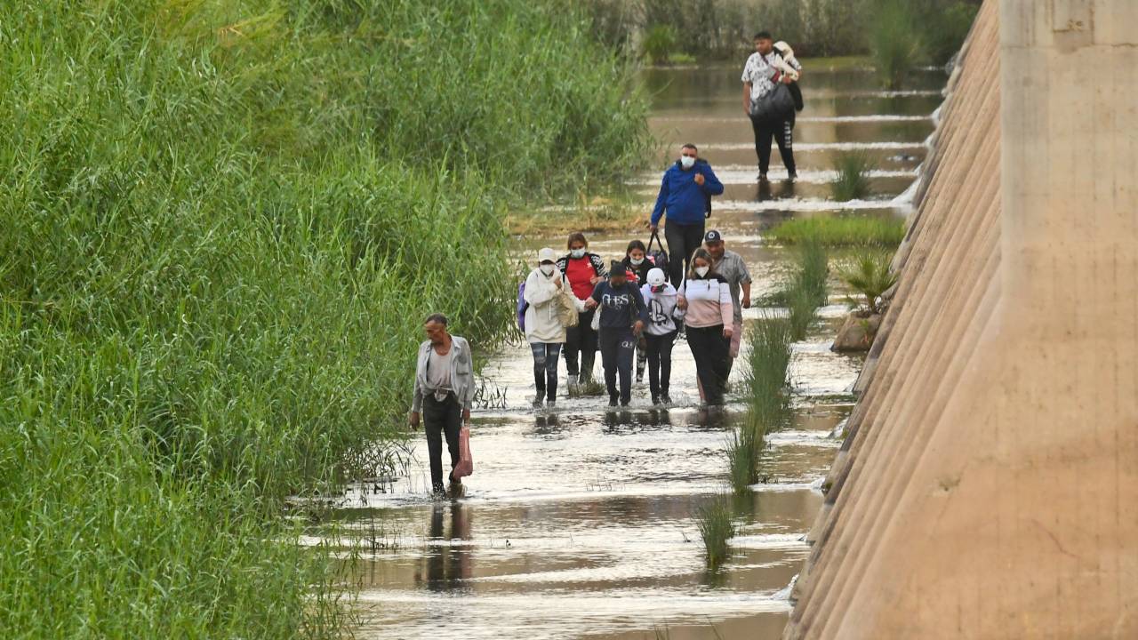 Um grupo de pessoas cruza a fronteira México-EUA.