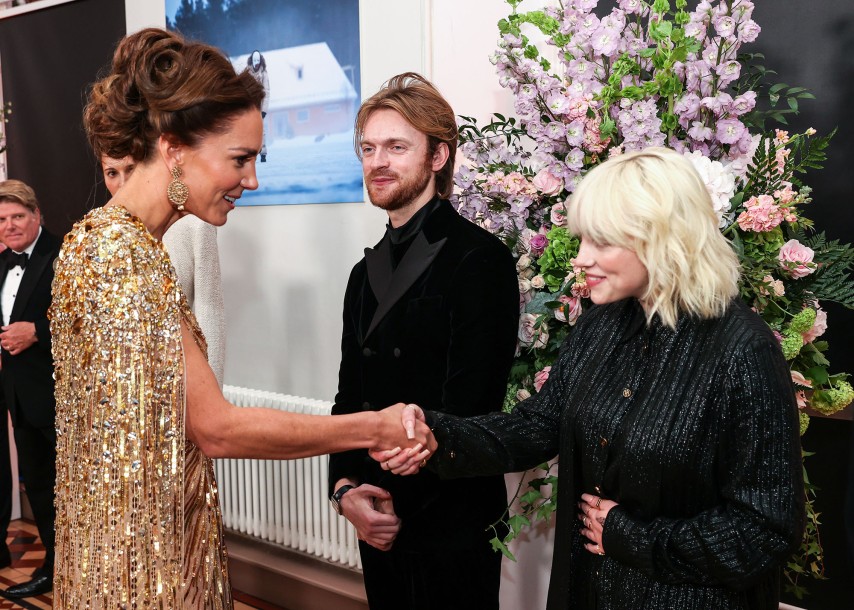A imagem mostra Kate MIddleton e a cantora Billie Eilish cumprimentando-se com um aperto de mão