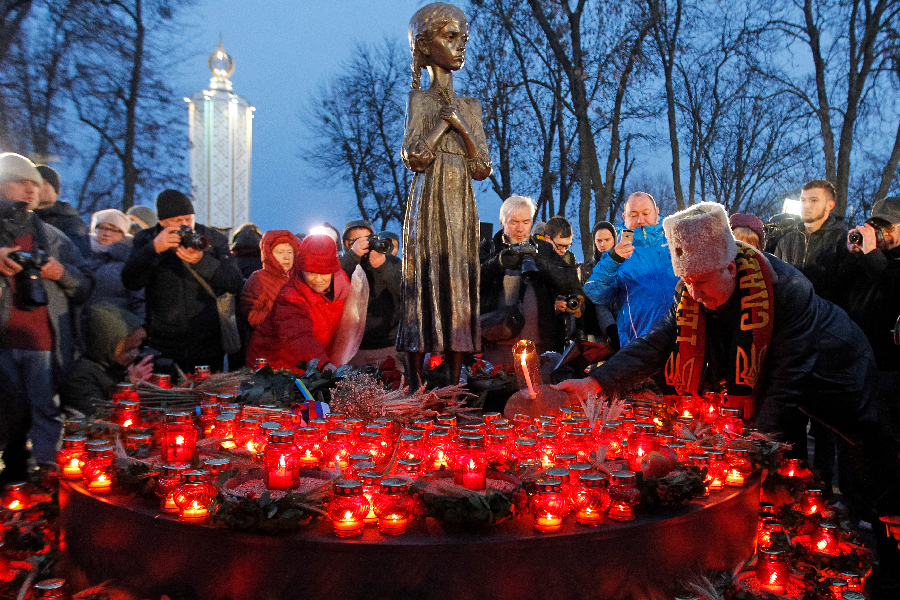 Ukrainians place candles and spikelets of wheat at the monument of victims during the event