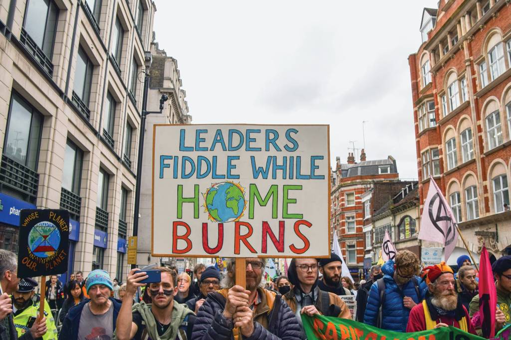 A demonstrator holds a placard which says ‘Leaders Fiddle PRESSÃO - Protesto durante a COP26, em Glasgow: exigência de agenda sustentável -
