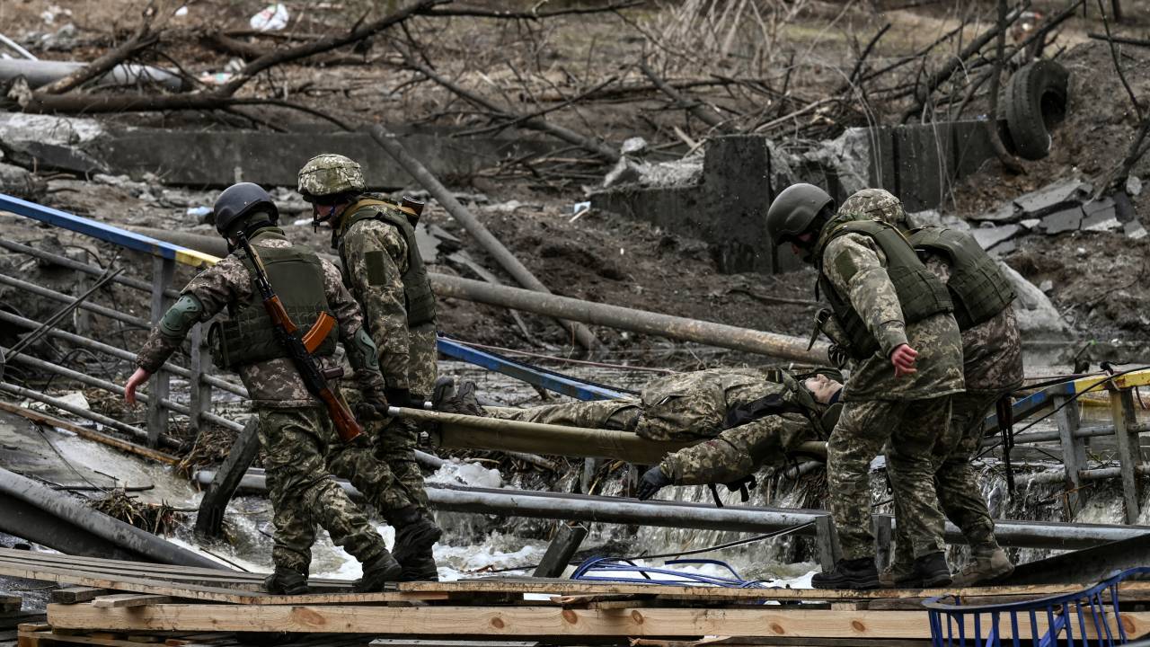 EDITORS NOTE: Graphic content / Ukranian servicemen carry the body of a comrade on a stretcher in the city of Irpin, northwest of Kyiv, on March 13, 2022. - Russian forces advance ever closer to the capital from the north, west and northeast. Russian strikes also destroy an airport in the town of Vasylkiv, south of Kyiv. A US journalist was shot dead and another wounded in Irpin, a frontline northwest suburb of Kyiv, medics and witnesses told AFP. (Photo by Aris Messinis / AFP)
