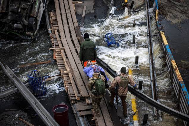 Militares ucranianos carregam uma idosa em uma maca em um caminho improvisado para atravessar um rio próximo a uma ponte destruída enquanto as pessoas fogem da cidade de Irpin, a noroeste de Kiev - Militares ucranianos carregam uma idosa em uma maca em um caminho improvisado para atravessar um rio próximo a uma ponte destruída enquanto as pessoas fogem da cidade de Irpin, a noroeste de Kiev -