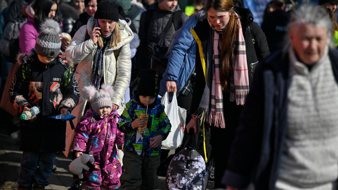 Refugees from Ukraine arrive to take further transport after crossing the Ukrainian border with Poland, at the Medyka border crossing, southeastern Poland, on March 13, 2022. - The number of refugees fleeing Ukraine since the Russian invasion two weeks ago is now nearly 2.6 million, the UN said on March 12, 2022. (Photo by Louisa GOULIAMAKI / AFP)