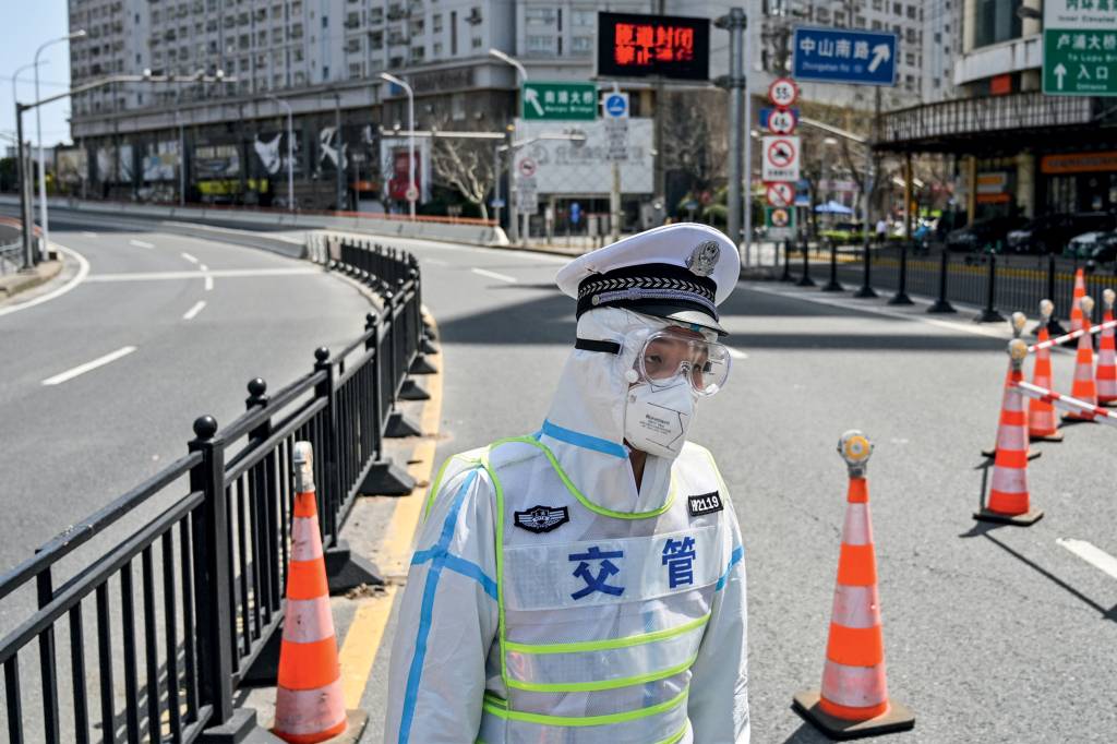 CHINA-HEALTH-VIRUS A transit officer, wearing a protective gear, controls access to a bridge in the direction of Pudong district in lockdown as a measure against the Covid-19 coronavirus, in Shanghai on March 29, 2022. (Photo by Hector RETAMAL / AFP)