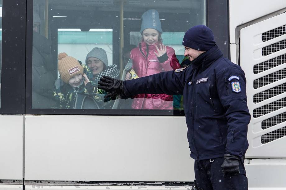 Um oficial da Gendarmaria romena sorri para refugiados ucranianos em um ônibus na fronteira romeno-ucraniana, em Siret -