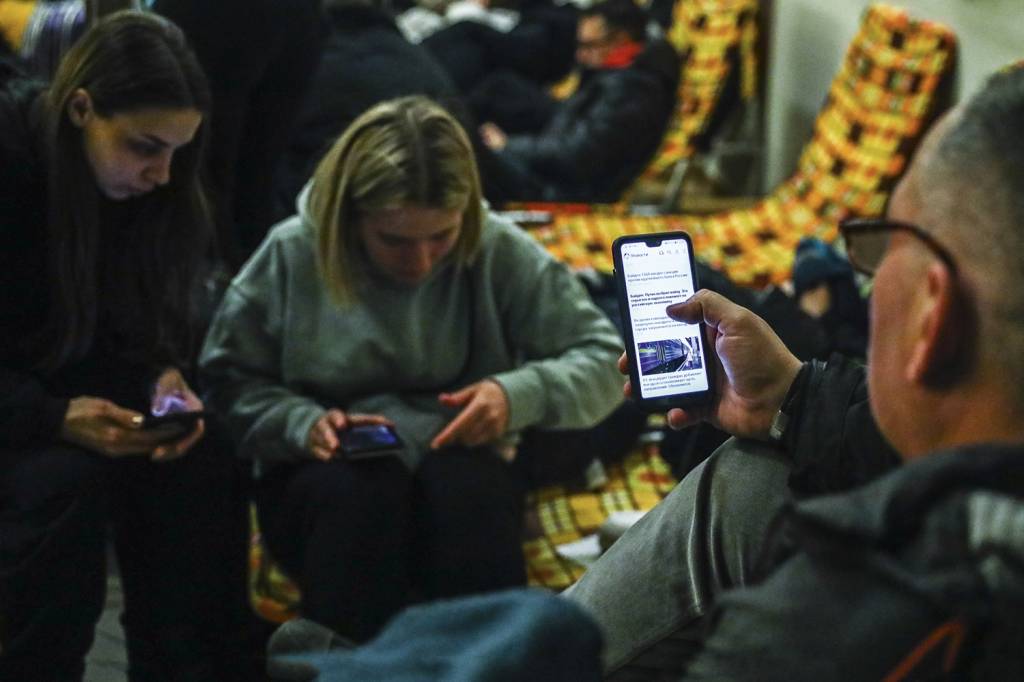 GettyImages-1238739920.jpg INFORMAÇÃO - Moradores de Kiev acompanham a guerra através dos celulares em abrigo: fator de mobilização da população -