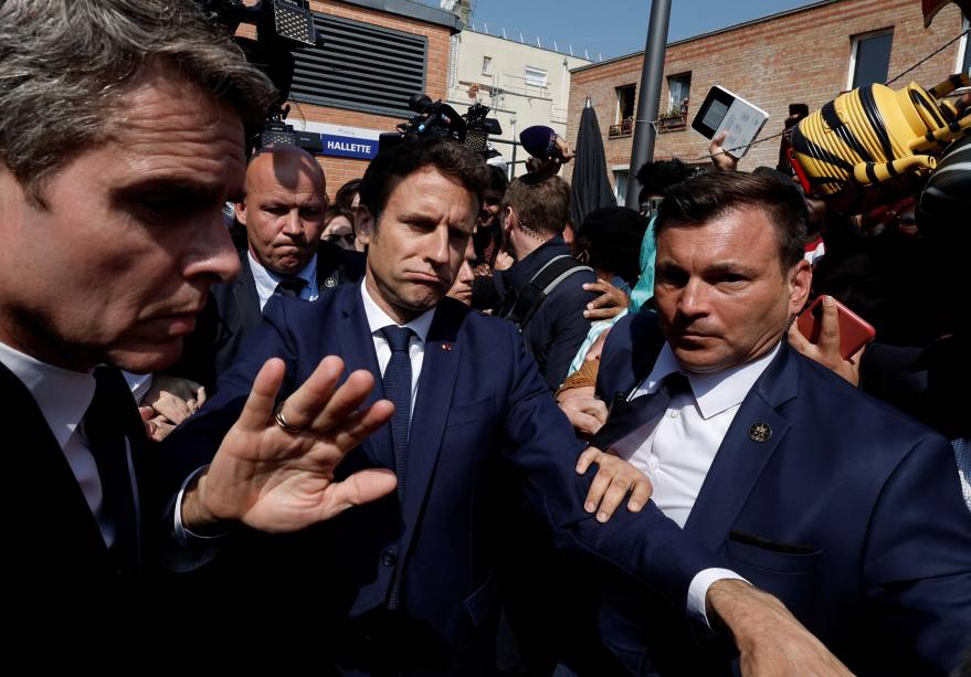 O presidente francês Emmanuel Macron com moradores, durante uma caminhada na praça do mercado Saint-Christophe em Cergy, subúrbio de Paris, França, 27 de abril de 2022.