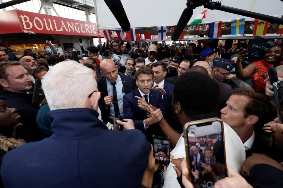 O presidente francês Emmanuel Macron com moradores, durante uma caminhada na praça do mercado Saint-Christophe em Cergy, subúrbio de Paris, França, 27 de abril de 2022.